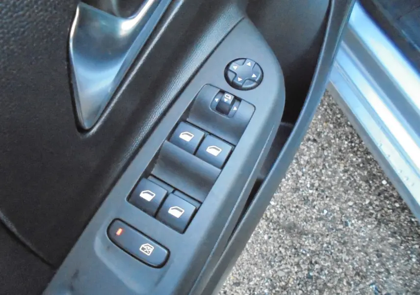 Gros plan sur les commandes des vitres électriques côté gauche de la porte avant d'une Opel Corsa gris quartz métal.
