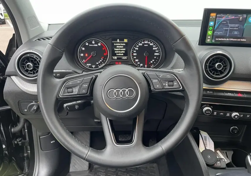 Vue intérieure centrée sur le volant cuir multifonction et le tableau de bord numérique de l'Audi Q2 2023.