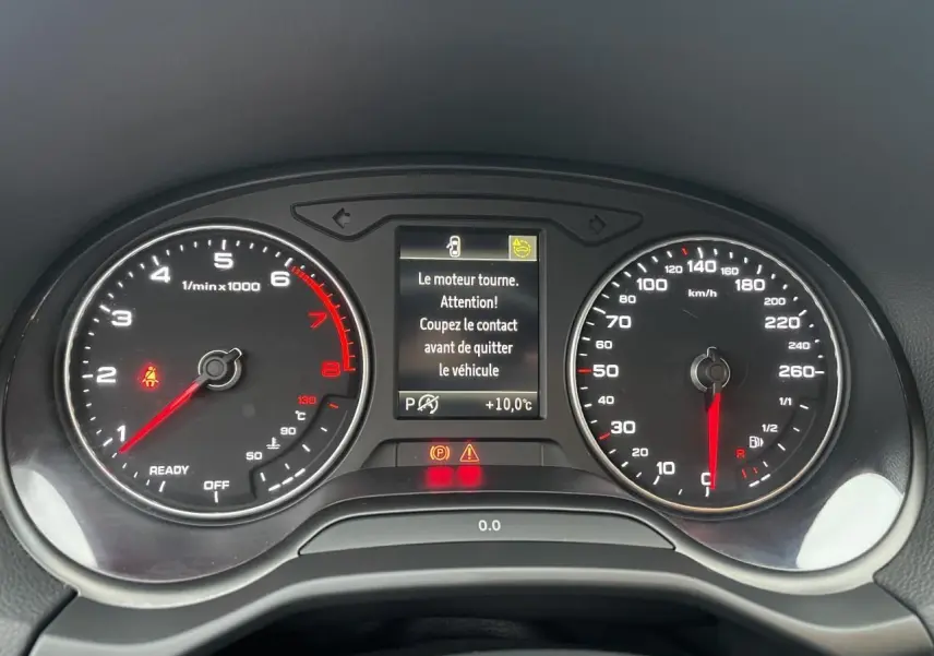 Tableau de bord d'Audi Q2 2023 avec compte-tours, vitesse, et écran central affichant un message d'alerte moteur.