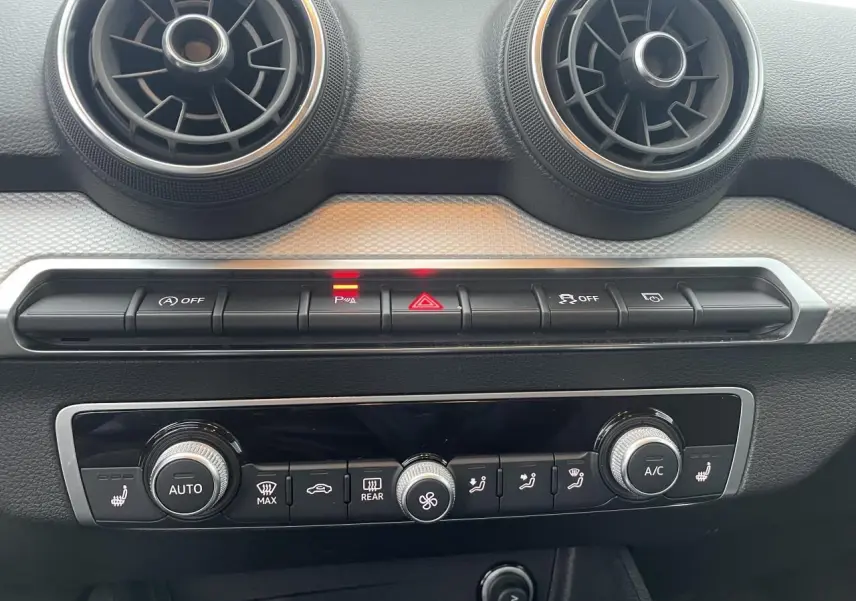 Vue rapprochée de la console centrale de l’Audi Q2 35 TFSI 2023, avec commandes climatisation et aérateurs ronds.