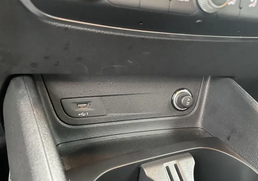 Gros plan sur la console centrale noire de l'Audi Q2 2023, avec prise USB et allume-cigare 12V visibles.