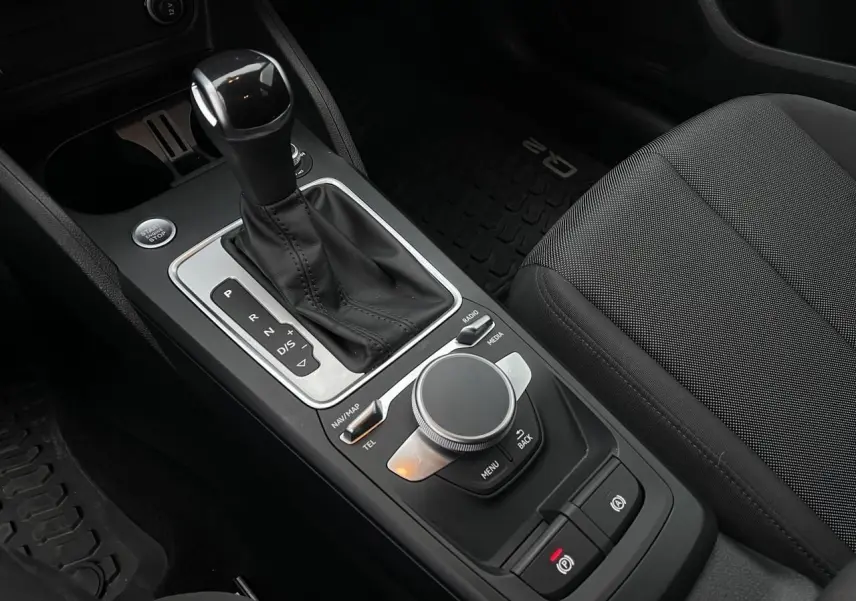 Vue rapprochée de la console centrale noire de l'Audi Q2 2023 avec levier de vitesse automatique et molette MMI.