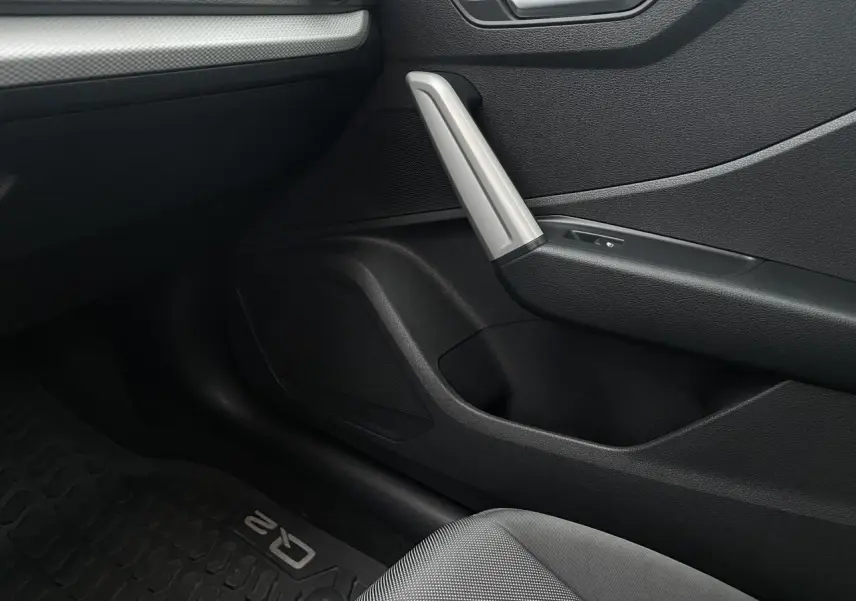 Détail intérieur côté passager de l'Audi Q2 2023, montrant la porte avec poignée argentée et tapis de sol marqué Q2.