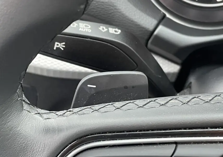 Gros plan sur la palette de changement de vitesse derrière le volant cuir noir de l'Audi Q2 35 TFSI 2023.