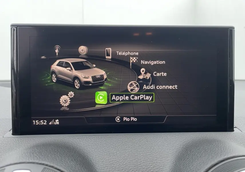 Écran central de l'Audi Q2 2023 affichant le menu Apple CarPlay avec une miniature du SUV gris clair.