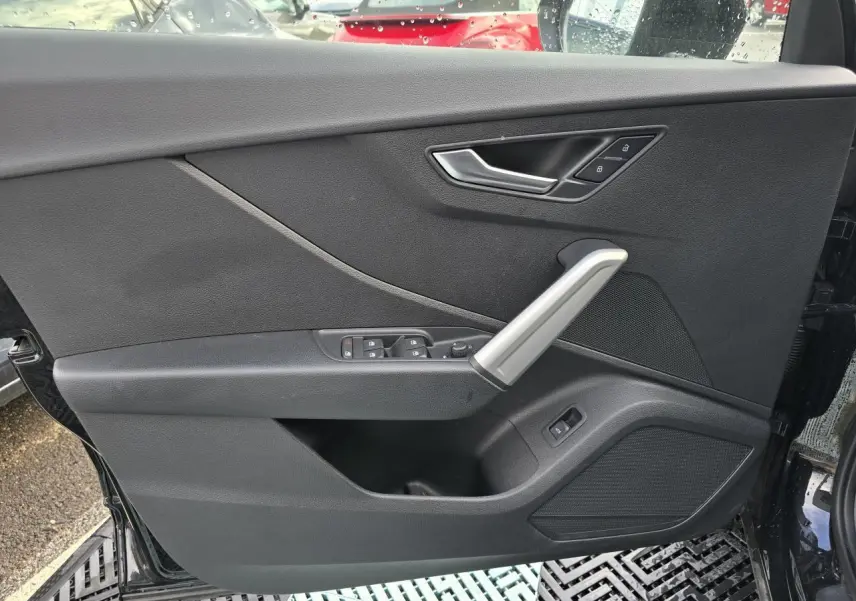 Vue intérieure de la porte avant gauche noire mythic de l'Audi Q2 2023 avec commandes de vitres et verrouillage.