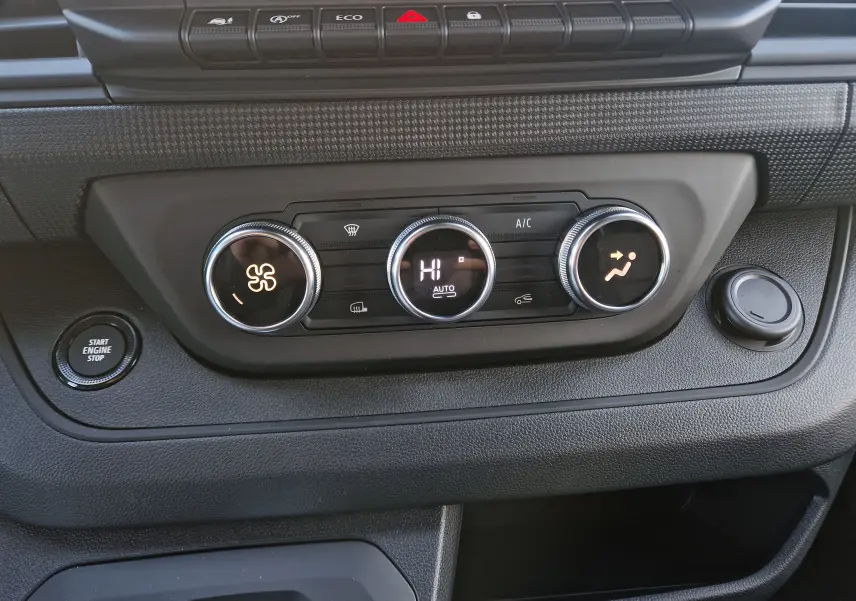Vue rapprochée du tableau de bord du Renault Trafic Fourgon 2025, avec commandes de climatisation et bouton start/stop.