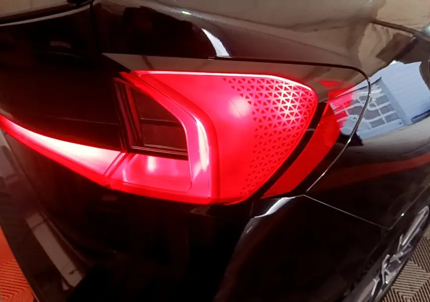 Gros plan sur le feu arrière gauche rouge du BMW X1 xDrive23i M Sport noir, soulignant ses motifs triangulaires distinctifs.