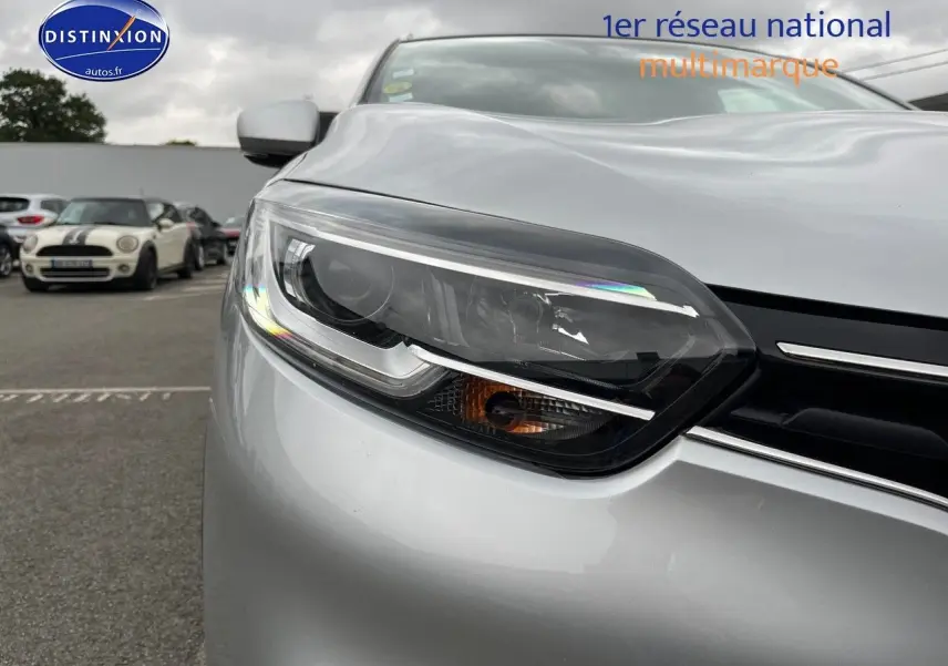 Gros plan sur le phare avant gauche du Renault Kadjar gris platine, soulignant la calandre et le capot lisse.