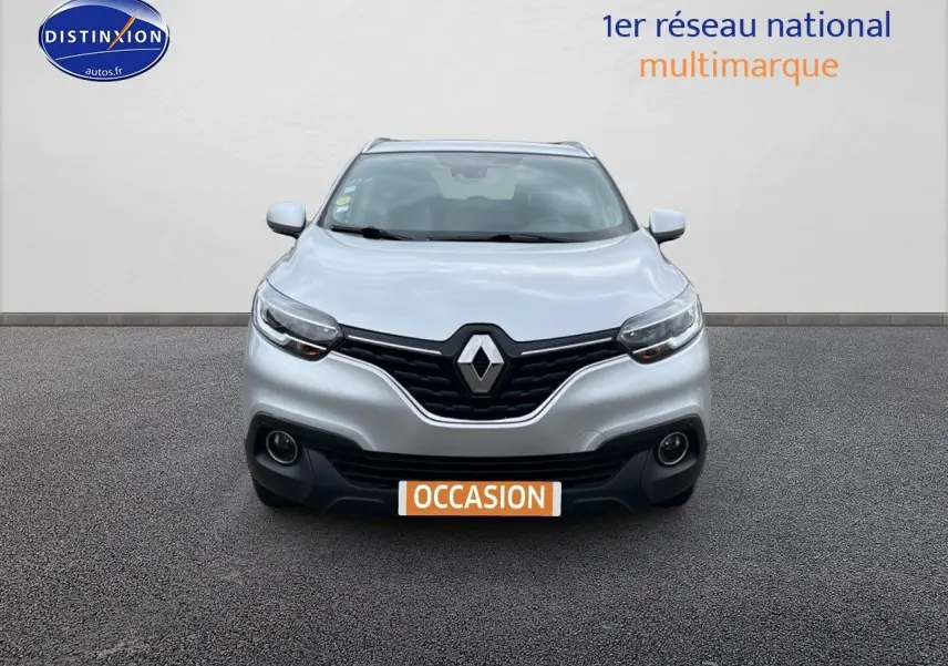Vue frontale d'un Renault Kadjar gris platine avec calandre noire et phares allumés sur fond neutre.