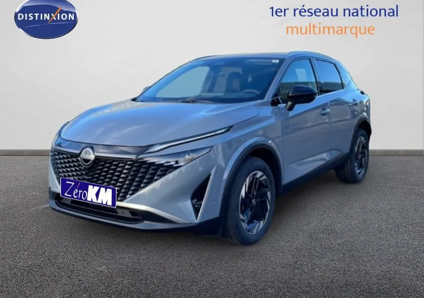 Nissan Qashqai gris argile métal en 3/4 avant droit, mettant en valeur sa calandre noire et ses jantes noires bicolores.