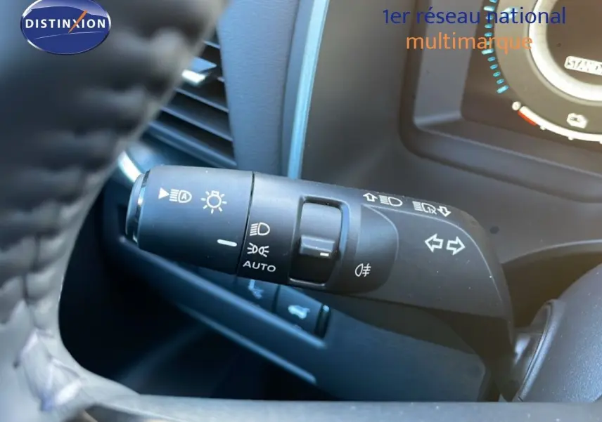 Gros plan sur la commande des phares à gauche du volant dans l'habitacle du Nissan Qashqai gris argile métal 2025.