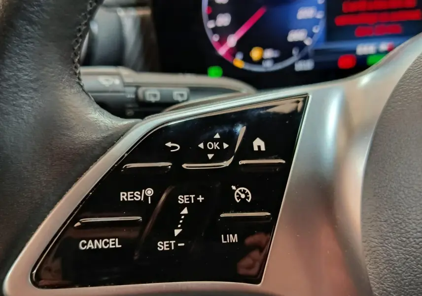 Gros plan sur le volant cuir et alu de la Mercedes Classe A 250 e Business Line 2023 avec commandes tactiles multifonctions.