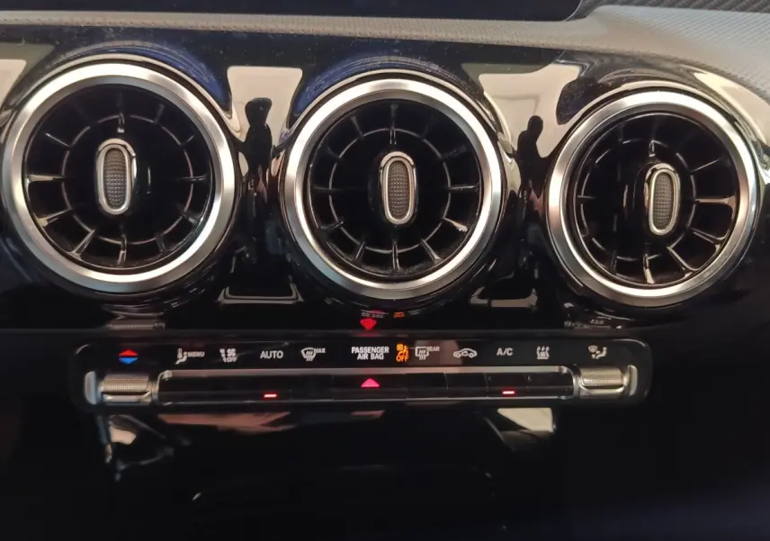 Détail du tableau de bord de la Mercedes Classe A 250 e Business Line 2023, montrant les aérateurs ronds et commandes climatisation.