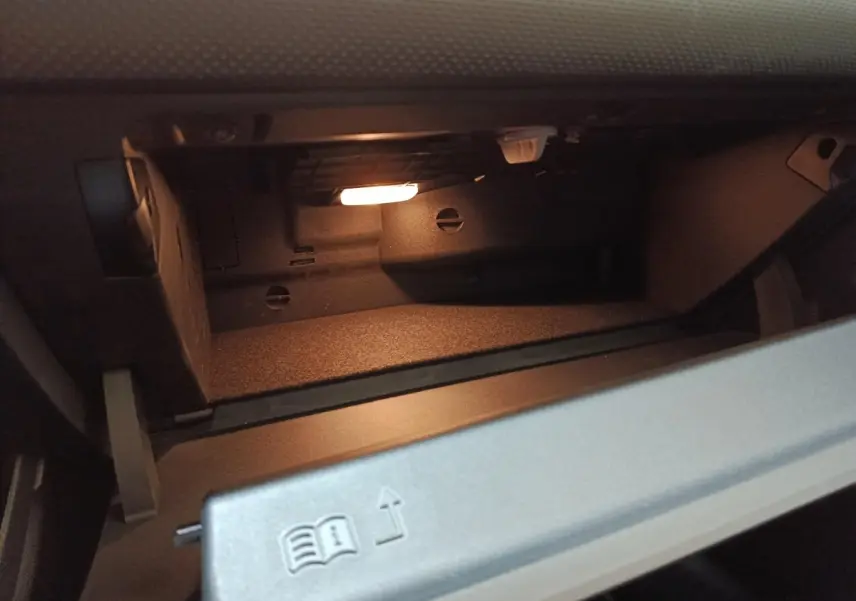 Intérieur de la boîte à gants éclairée de la Mercedes Classe A 250 e Business Line gris clair, vue rapprochée.