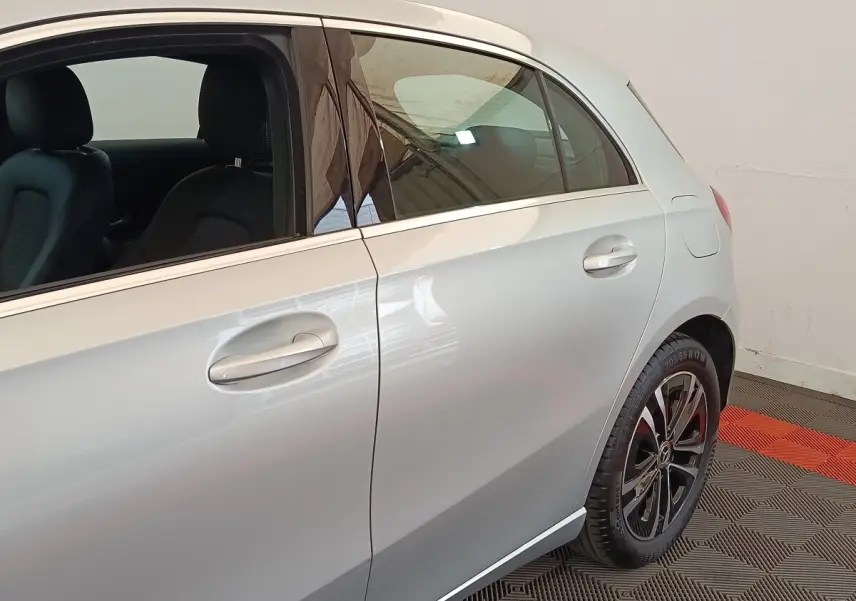 Vue latérale côté droit d'une Mercedes Classe A 250 e Business Line gris clair avec jantes alliage noires et intérieurs cuir noirs.