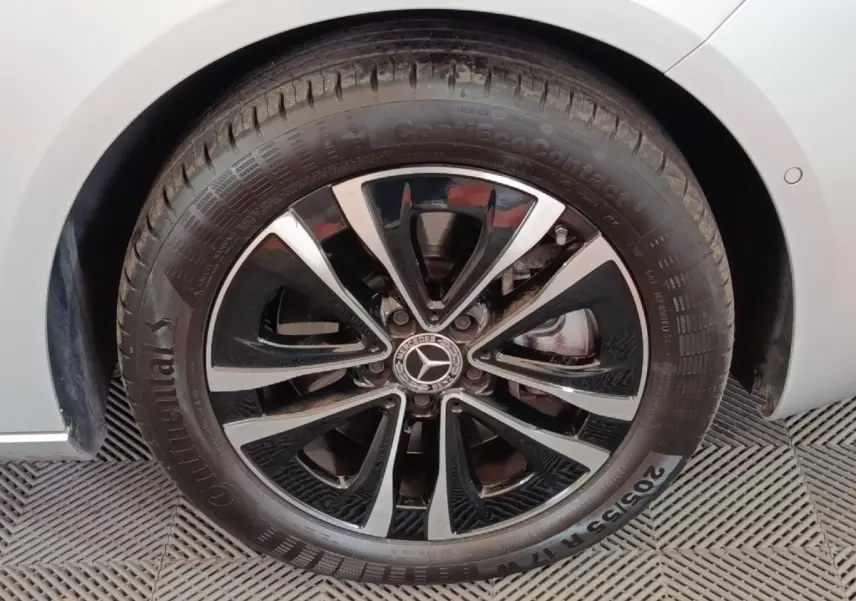 Gros plan sur la roue avant droite d’une Mercedes Classe A gris clair avec jante alliage noir et argentée.