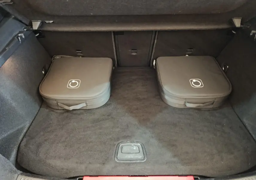 Coffre ouvert d’une Mercedes Classe A 250 e Business Line 2023, avec deux sacs de chargeurs hybrides gris foncé posés au fond.