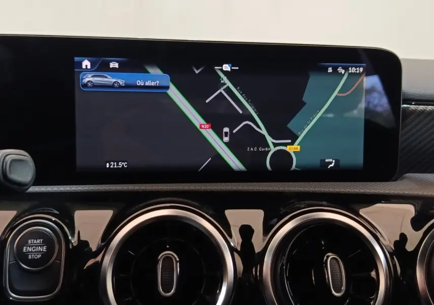 Vue rapprochée de l’écran tactile central et des aérateurs ronds chromés du tableau de bord noir brillant d’une Mercedes Classe A 250 e.