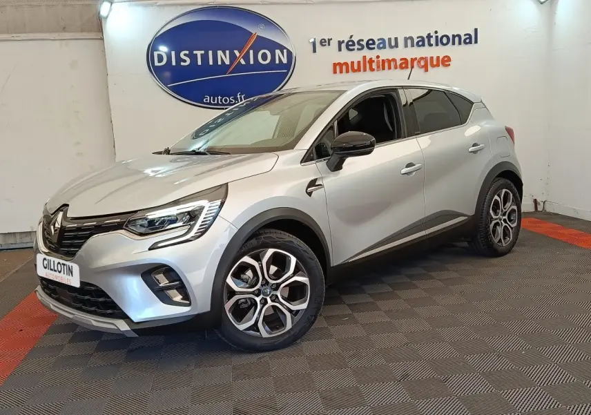 Renault Captur Intens E-TECH gris clair en 3/4 avant droit, avec jantes alliage et feux LED allumés.