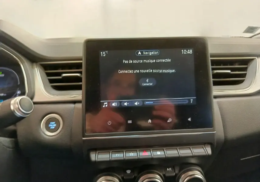 Vue rapprochée du tableau de bord du Renault Captur gris clair, écran tactile central avec commandes et bouton démarrage.