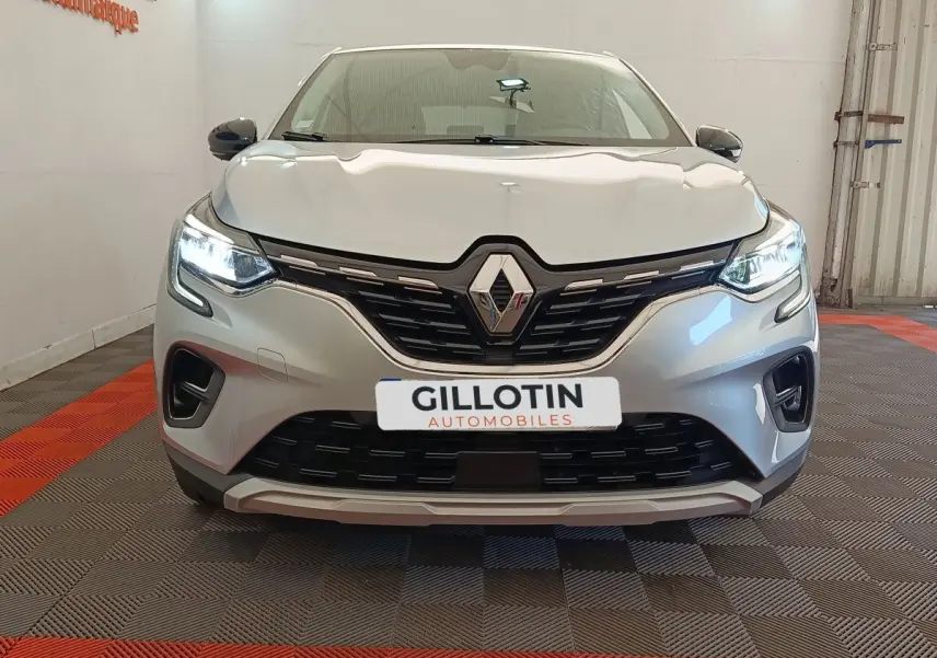 Vue frontale d'un Renault Captur gris clair avec phares LED allumés et calandre noire distinctive.