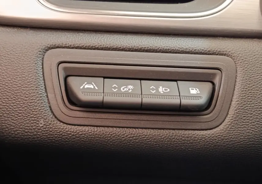 Gros plan sur les boutons de commande d'assistance et éclairage du tableau de bord du Renault Captur gris clair Intens E-TECH.