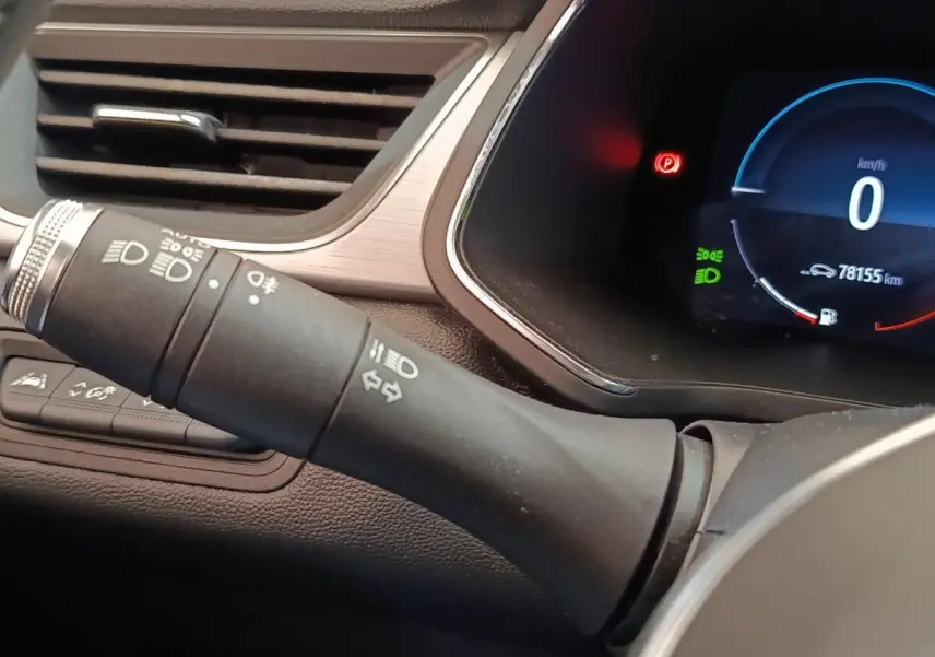 Gros plan sur la commande des feux et le combiné d'instruments numérique du tableau de bord du Renault Captur gris clair.