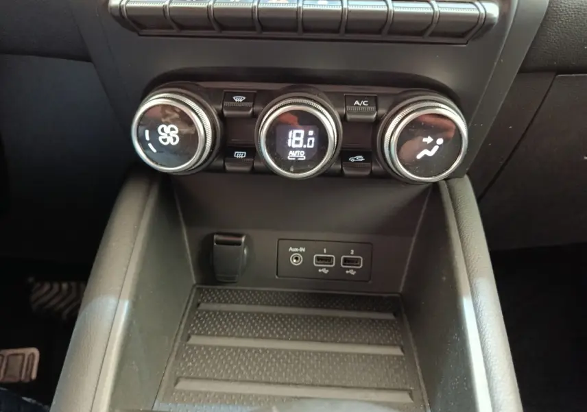 Vue rapprochée de la console centrale du Renault Captur gris clair 2021, avec commandes climatisation et ports USB visibles.