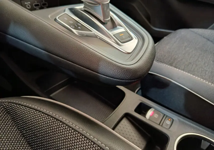 Gros plan intérieur sur la console centrale et levier de vitesse automatique du Renault Captur Intens E-TECH gris clair.