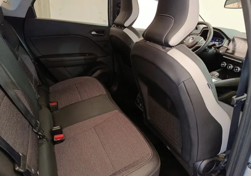 Vue intérieure côté arrière droit du Renault Captur Intens E-TECH 2021, sièges tissu gris et noir avec tableau de bord visible.