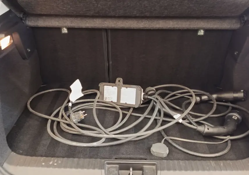 Coffre ouvert d’un Renault Captur gris clair 2021 avec câble de recharge hybride posé à plat.
