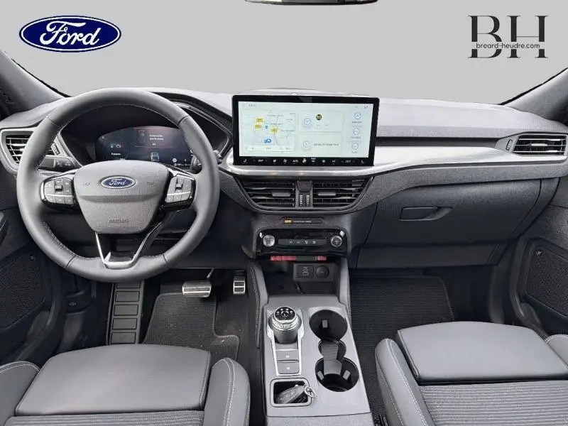 Vue intérieure avant du Ford Kuga 2026 avec tableau de bord moderne, écran tactile central et volant multifonction gris.