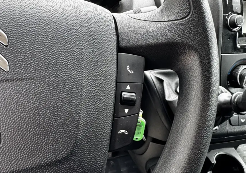 Gros plan sur le volant multifonctions noir du Citroën Jumper blanc, avec commandes d’appel téléphonique visibles.