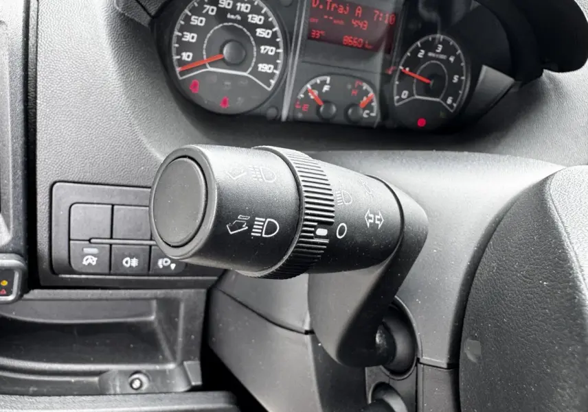 Gros plan sur la commande des phares et clignotants du tableau de bord d'un Citroën Jumper blanc, vue côté conducteur.