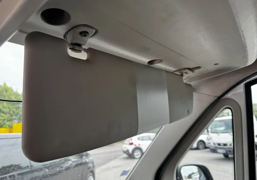 Détail intérieur du pare-soleil côté conducteur du Citroën Jumper blanc, vue vers l’avant avec rétroviseur et extérieur flou.