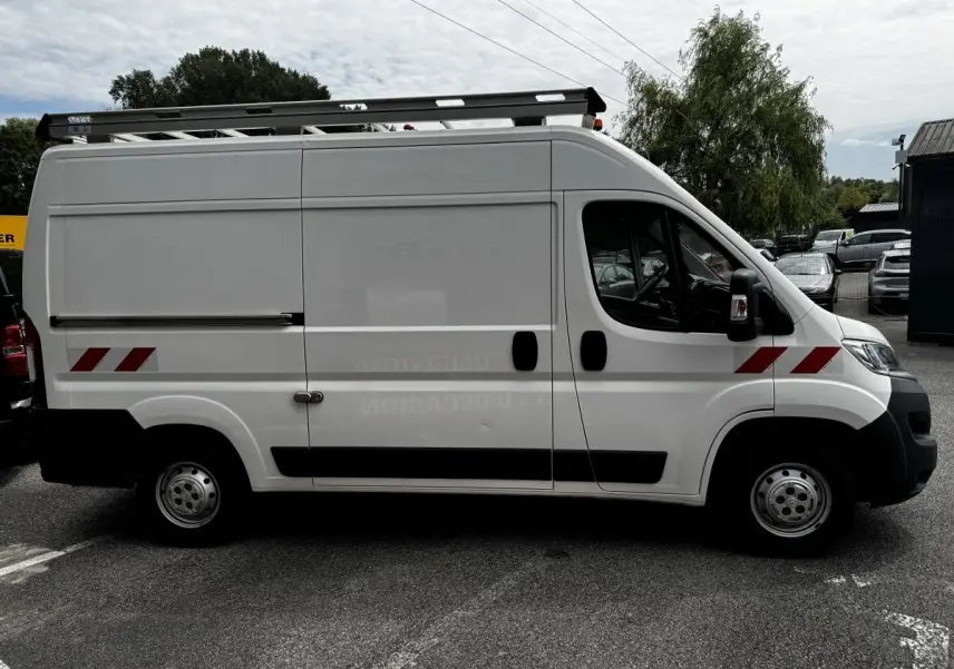 Vue latérale droite d’un utilitaire Citroën Jumper blanc avec marquages rouges et galerie de toit noire.
