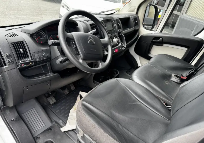 Vue intérieure côté conducteur du Citroën Jumper 2019, volant multifonctions, sièges noirs en cuir, tableau de bord et console centrale visibles.