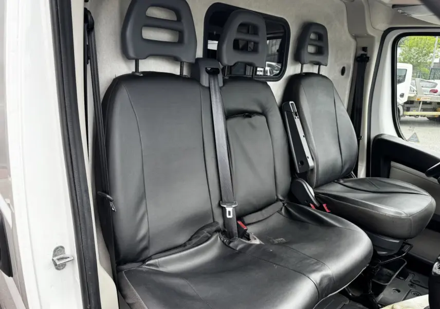 Vue intérieure côté conducteur du Citroën Jumper blanc 2019, sièges avant en cuir noir avec ceinture de sécurité centrale.