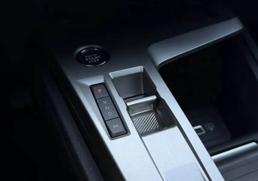 Gros plan sur la console centrale grise avec boutons de boîte auto et bouton start/stop du Peugeot 308 Hybrid 2025.