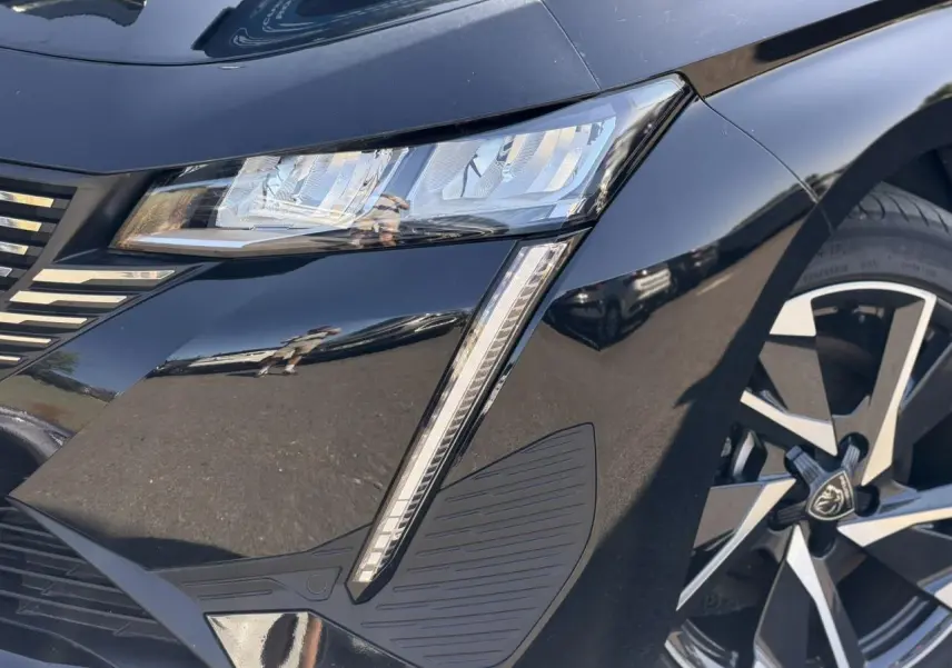 Gros plan sur l'avant droit noir Perla de la Peugeot 308 Hybrid avec feux LED et jante alliage 17 pouces.