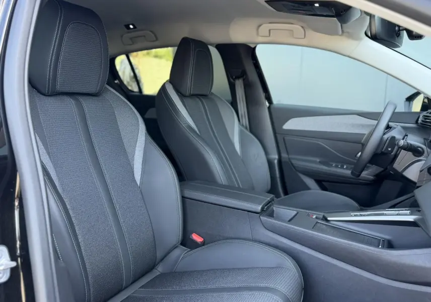 Vue intérieure côté gauche des sièges avant en sellerie tri matières TEP/tissu gris avec surpiqûres bleues dans une Peugeot 308 Hybrid 2025.