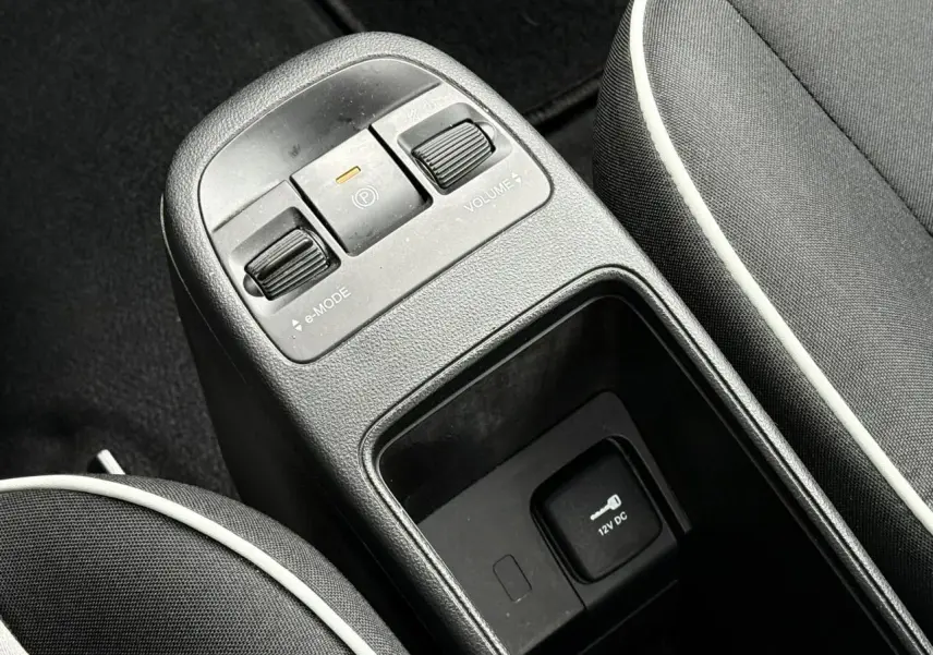 Gros plan sur la console centrale noire de la Fiat 500 électrique avec commandes e-mode et frein à main électrique.