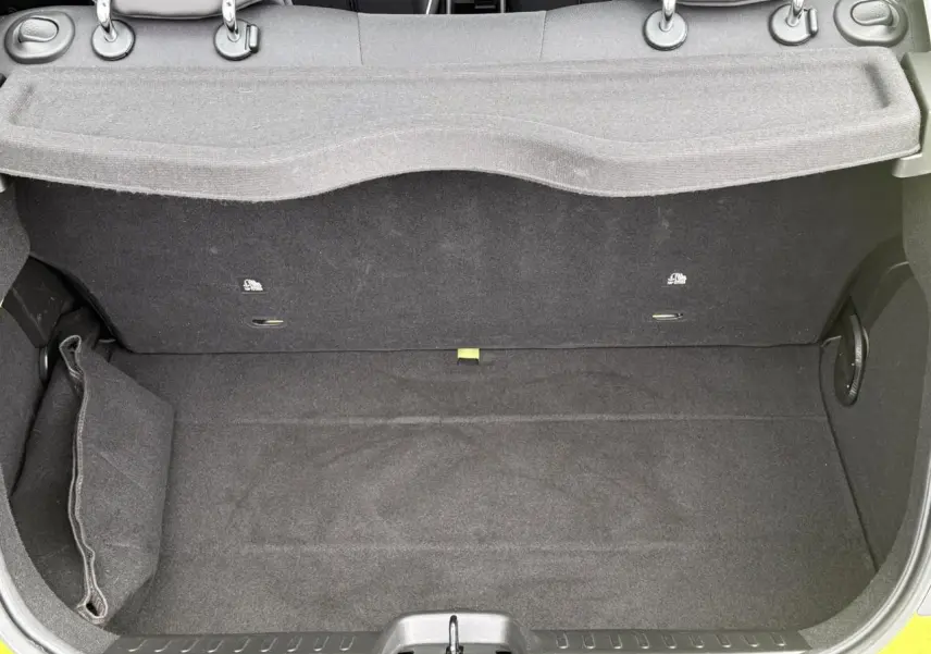 Coffre ouvert d'une FIAT 500 électrique 2024 en Jaune Acid, montrant un espace de rangement propre et tapissé de noir.