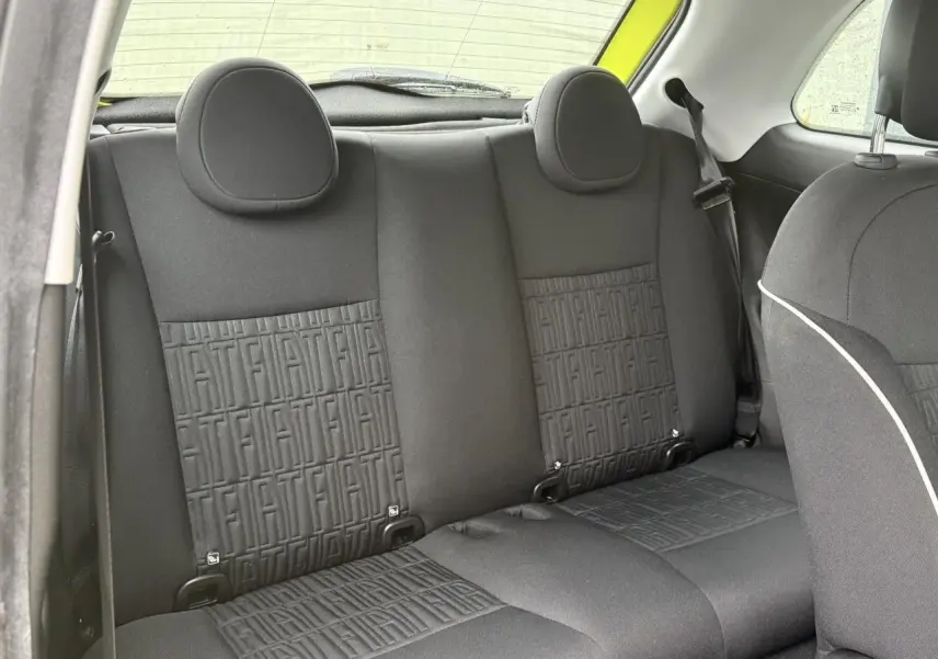 Vue intérieure arrière des sièges noirs avec motif FIAT embossé dans une Fiat 500 électrique jaune Acid 2024.