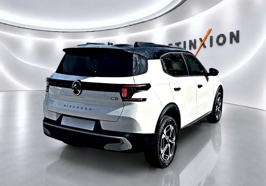 Vue 3/4 arrière droite du Citroën C3 Aircross blanc avec toit noir et jantes alu dans un showroom moderne.