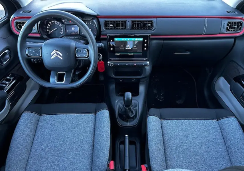 Intérieur avant de la Citroën C3 gris foncé, volant multifonction, tableau de bord avec écran tactile central et sellerie tissu gris.