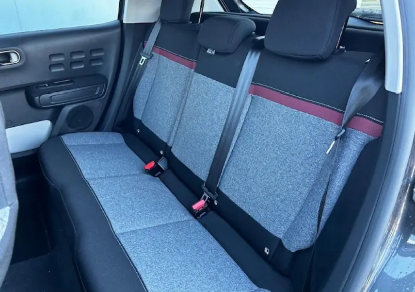 Banquette arrière grise avec bande rouge dans une Citroën C3 III vue côté gauche, intérieur clair et moderne.