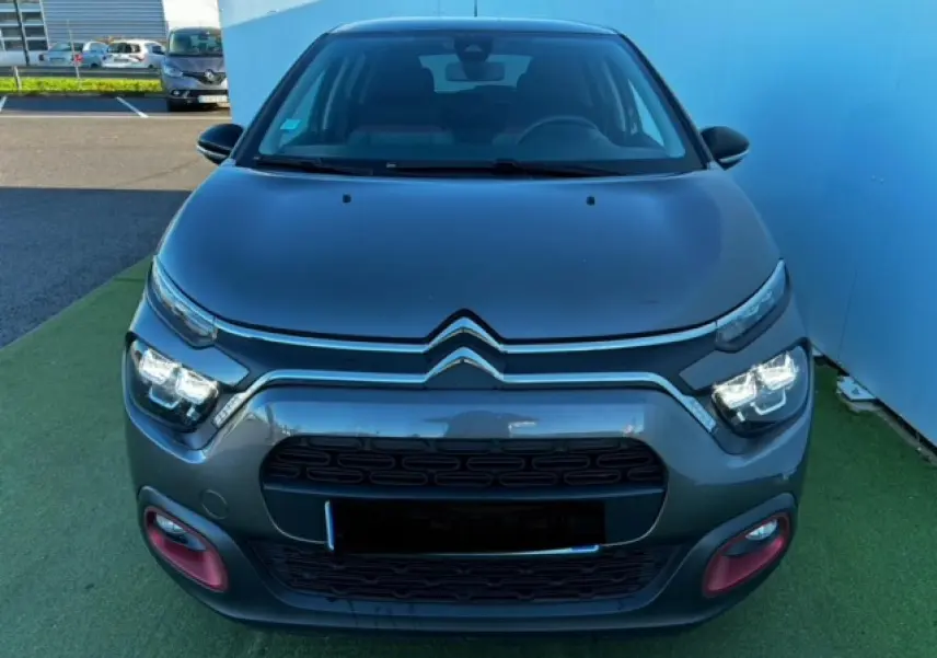 Vue frontale d'une Citroën C3 gris foncé avec signature lumineuse LED et entourages rouges sur le pare-chocs.