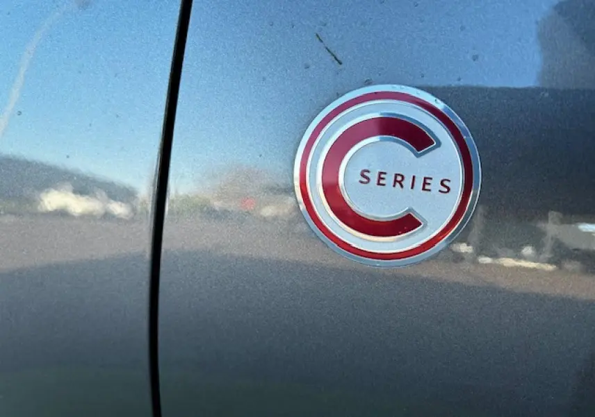 Gros plan sur le badge C-Series rouge et argent sur la porte d'une Citroën C3 gris foncé.
